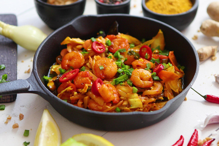 Shrimps fried on iron pan with vegetables and fresh herbs. Flat lay.